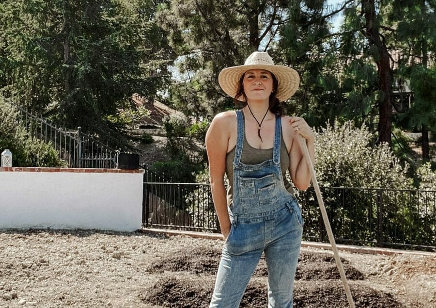 woman in overalls and hat with shovel in the garden