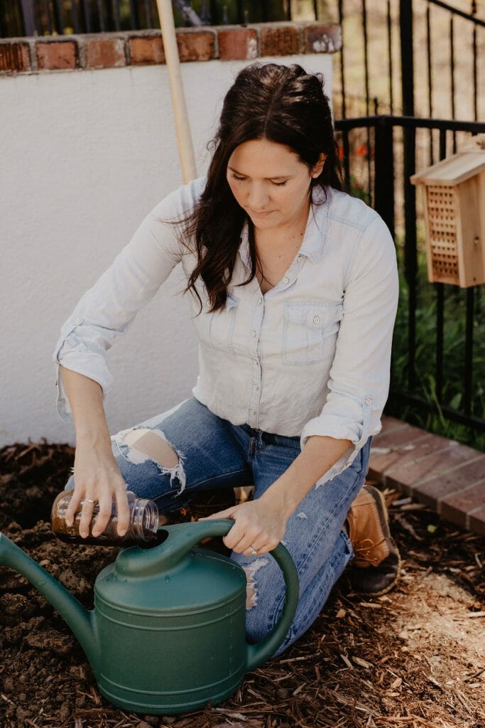 Woman adding fertilizer to watering can. 