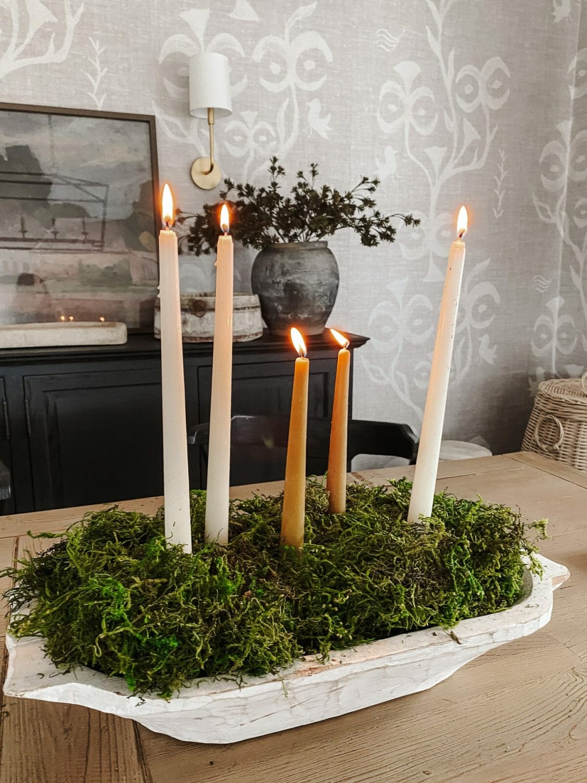 candles in wooden bowl with moss on table