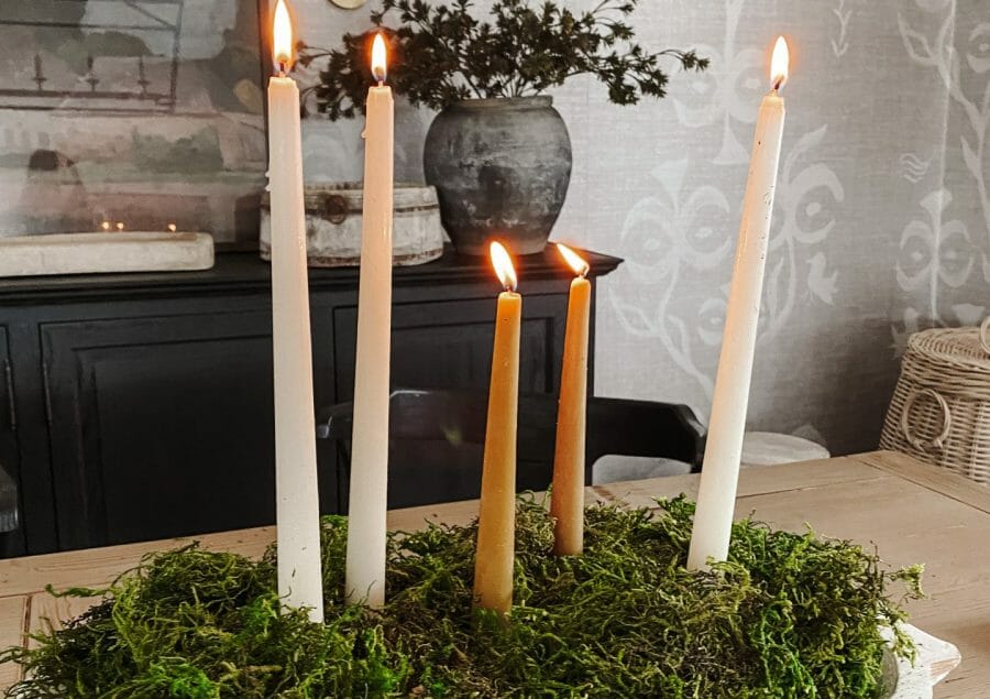 candles in wooden bowl with moss on table